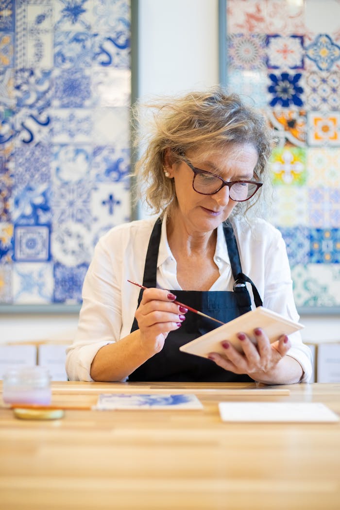 Senior woman creating ceramic artwork in a studio in Portugal, showcasing traditional art techniques.