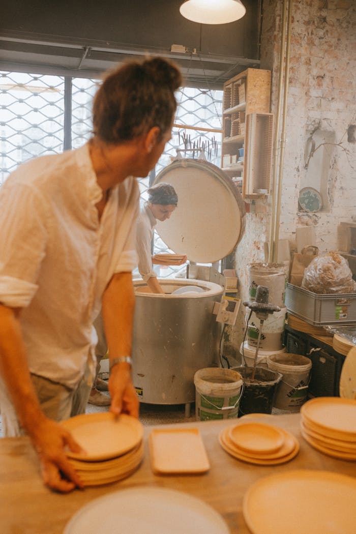 Two artisans skillfully crafting ceramic plates in a workshop, showcasing traditional pottery techniques.